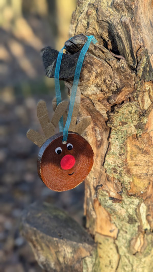 handmade reindeer decoration made from wood and cardboard is hanging from a blue ribbon on tree branch