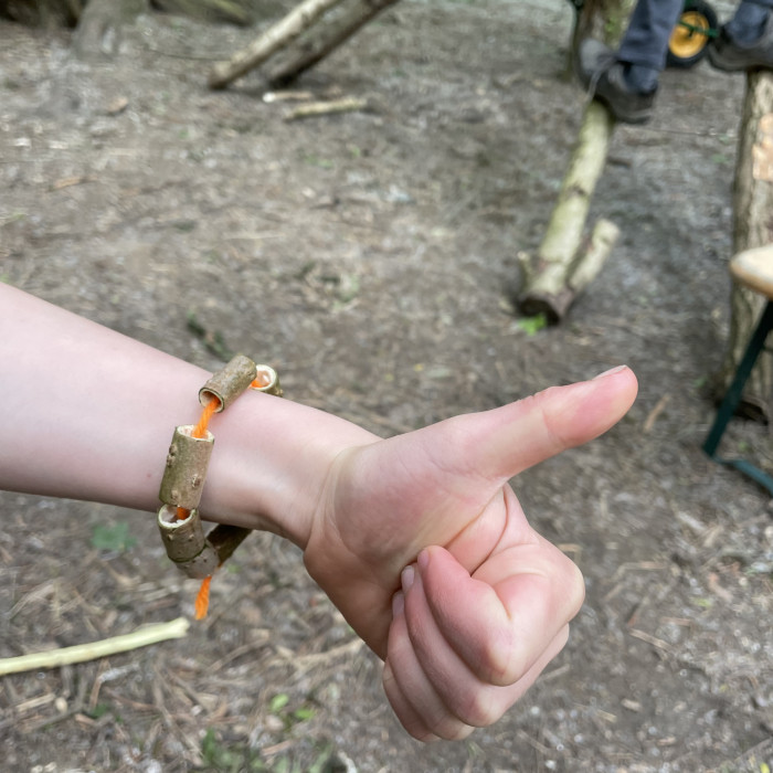 A childs hand is giving thumbs up while wearing a bushcraft bangle