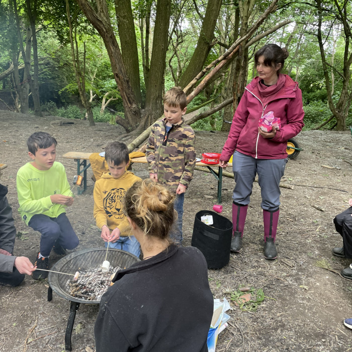 Three children and the tutors are making Campfire marshmallows