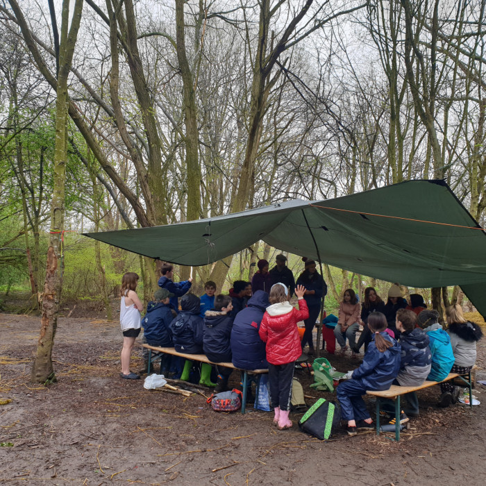 A group of chuildren gather under shelter to eat their lunches