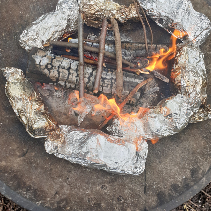 Foil parcels cooking food on the campfire