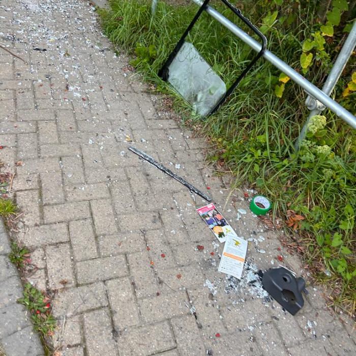 A trail of glass, vehicle parts including a car window frame and other debris litters the path all the way up to the environment centre garden