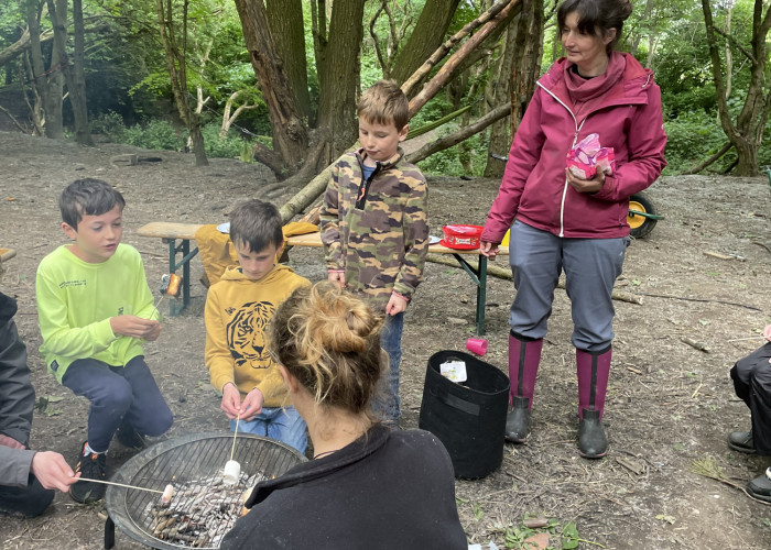 Three children and the tutors are making Campfire marshmallows