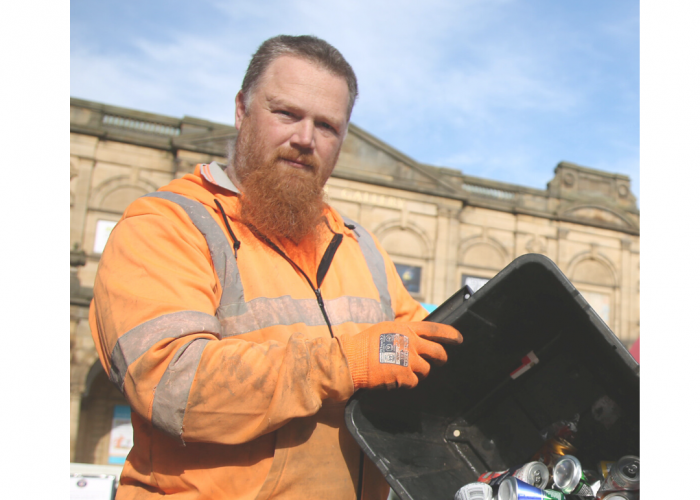 Stuart Watling a portly white red haired man with long beard looking into the camera he is tipping a box of aluminium into a bin
