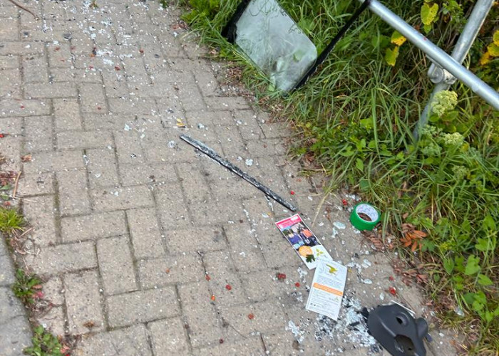 A trail of glass, vehicle parts including a car window frame and other debris litters the path all the way up to the environment centre garden