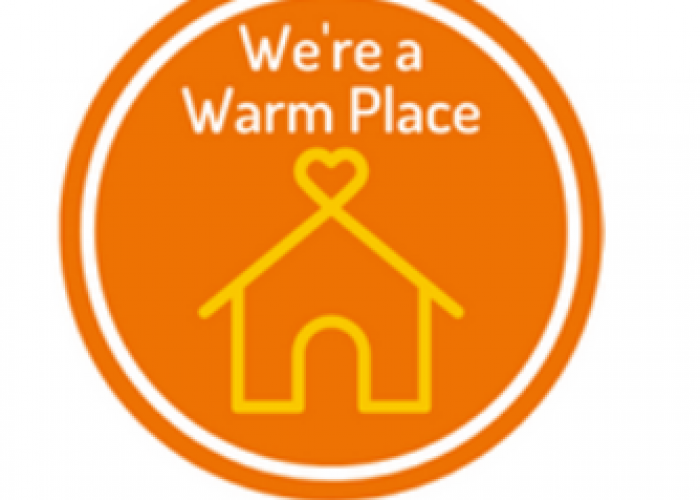 the logo for Warm spaces. It is an orange ring with a yellow house with a heart at the top and the words 